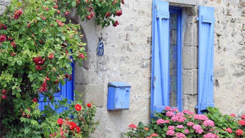 Blaue Fensterläden und roter Blumenschmuck, allgegenwärtig in der Bretagne.